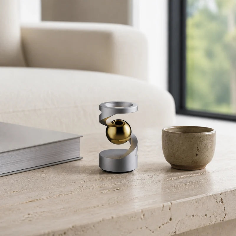 Silver levitation spinner with gold sphere on a travertine coffee table in a living room