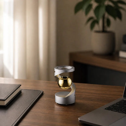 Silver levitation spinner with gold sphere on a walnut home office desk in morning light